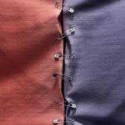 Blue and red swatches of cloth held together by safety pins.