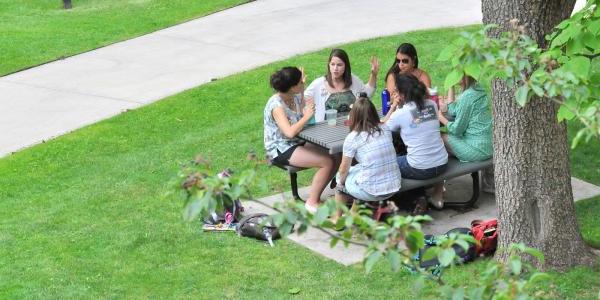 Students sitting at table outside the School of Education